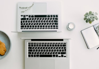 two silver laptop computers besides clear glass jar