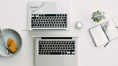 two silver laptop computers besides clear glass jar