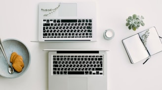 two silver laptop computers besides clear glass jar