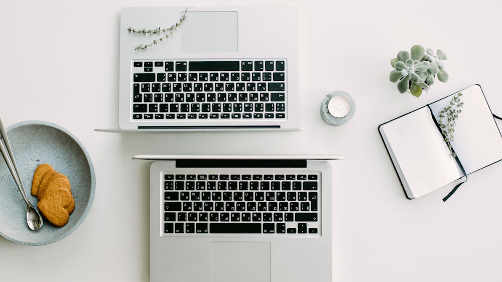 two silver laptop computers besides clear glass jar