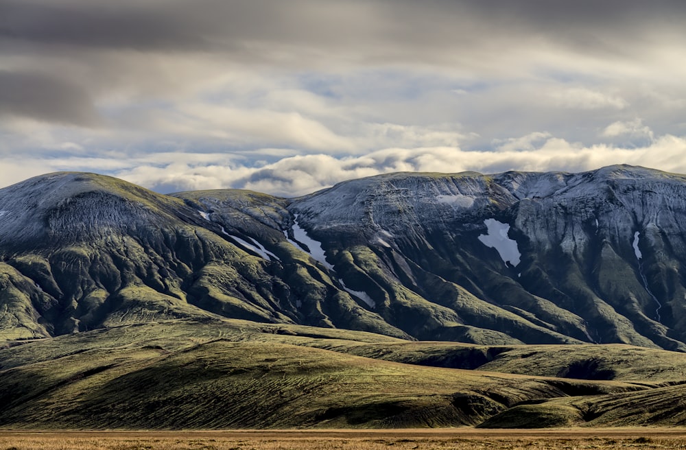 green and gray mountain under cloudy sky