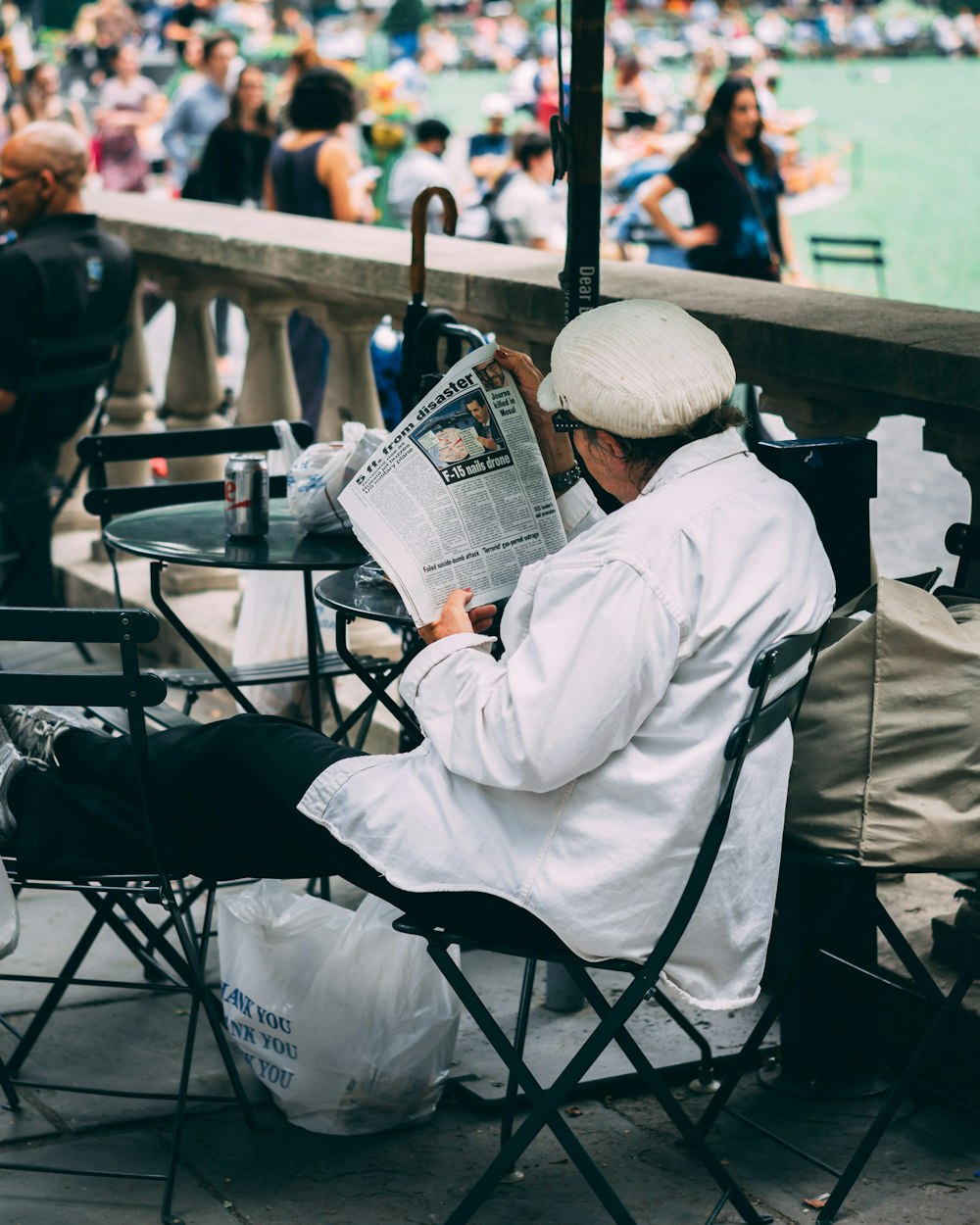 椅子に座り、水辺で新聞を読む女性