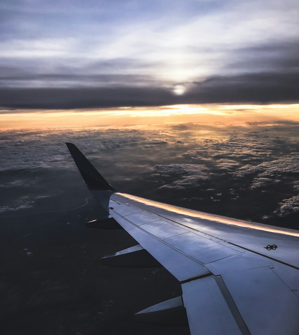 airplane on sky above white clouds during orange sunset