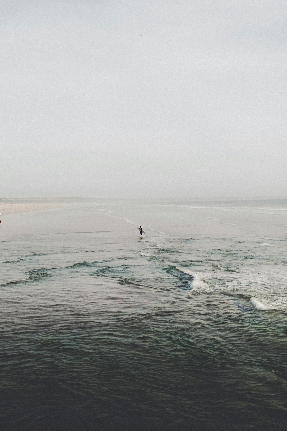 Persona che tiene la tavola da surf in uno specchio d'acqua