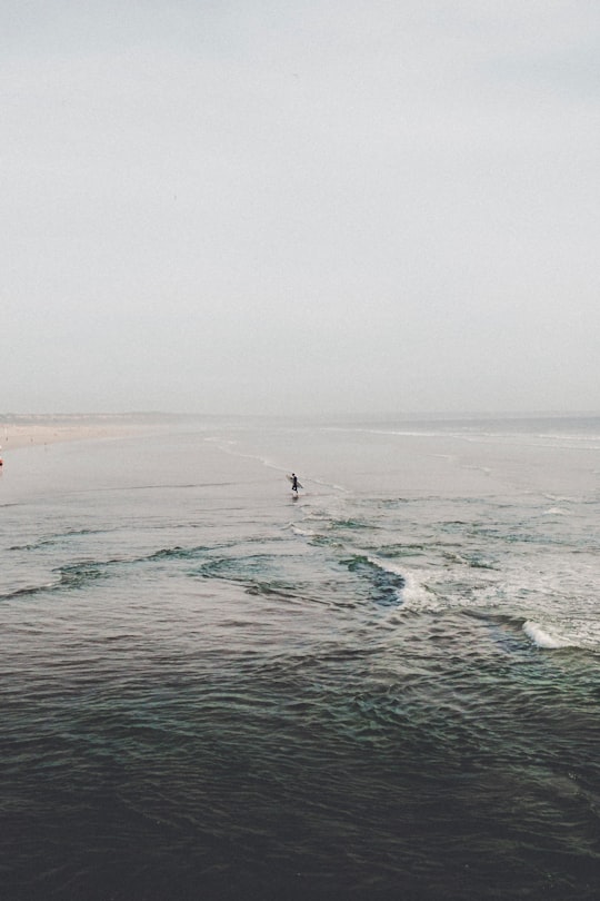 person holding surfboard in body of water in Costa da Caparica Portugal
