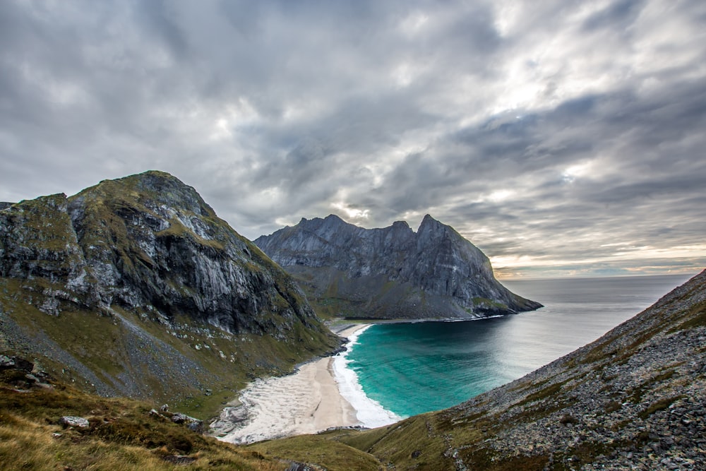 gray and green mountain beside body of water