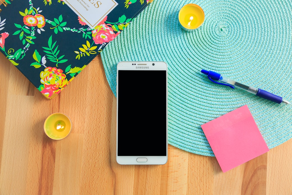 smartphone Samsung Galaxy bianco sopra la tovaglietta blu vicino alla penna a scatto blu