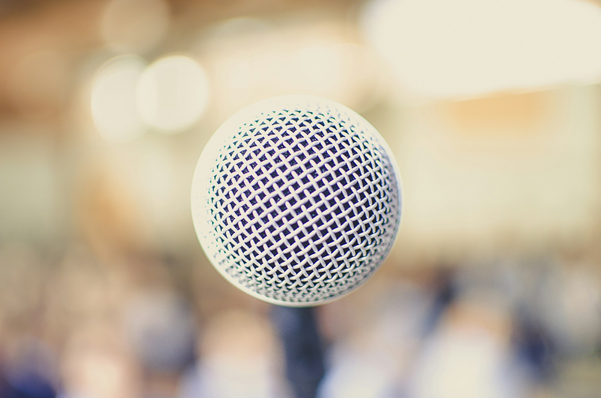 Close-up of a vintage microphone with the blue and white colors of Rádio Cena MPB softly blurred in the background.