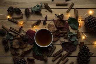 Warm cup of winter tea with steam rising surrounded by cinnamon sticks and dried herbs