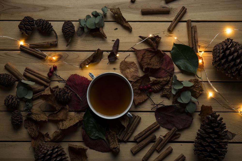 white ceramic mug ner dried leaves and orange string light