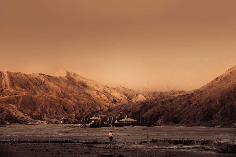 man walking towards building surrounded with mountain