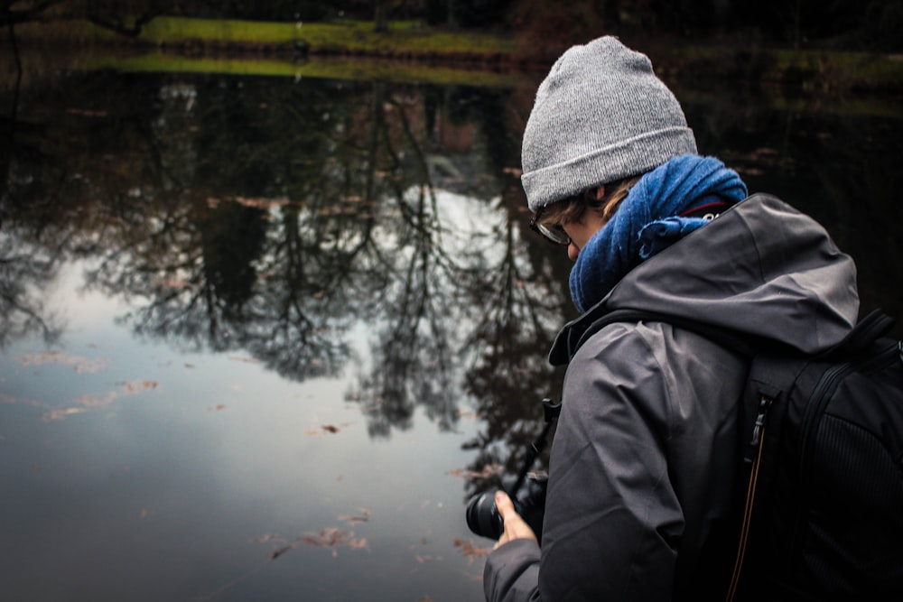 man holding camera infront of water