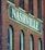 A brick building facade featuring a large sign painted with the word 'Nashville' in bold white letters. The structure has a vintage architectural style, characterized by arched windows and weathered brickwork.