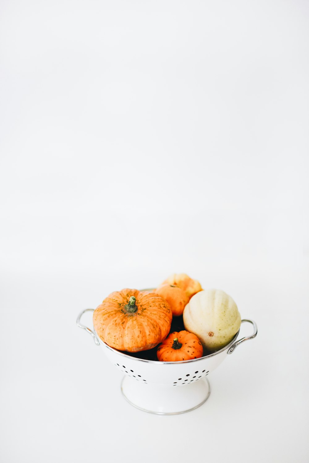 Quatro abóboras laranjas redondas em Colander