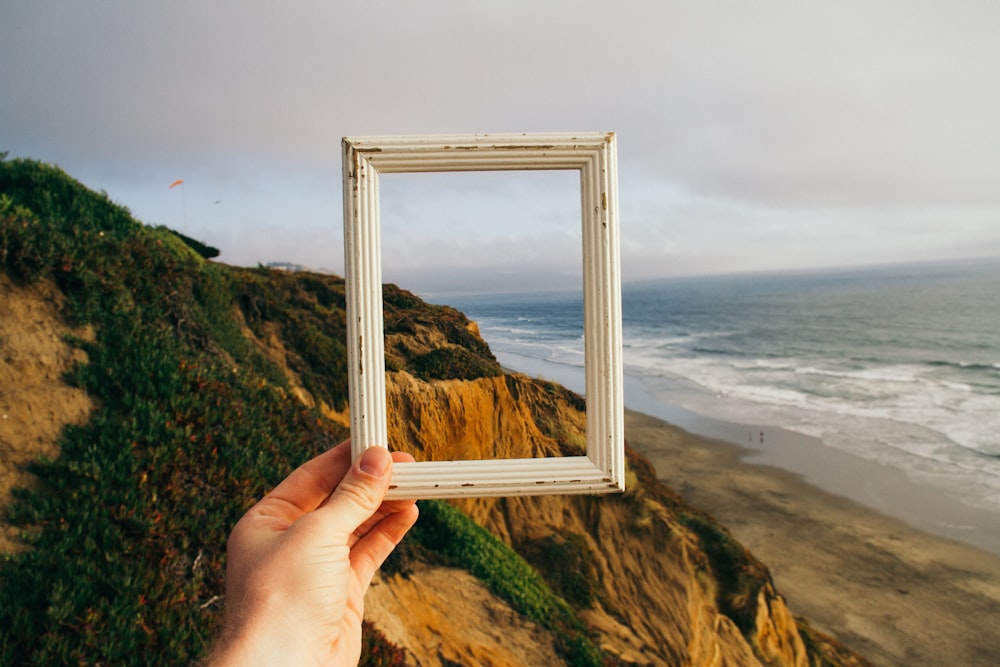 persona mano che tiene la cornice per foto