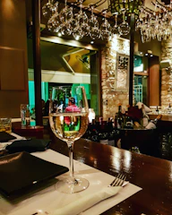 Glasses of chilled white wine catching the light on a rustic wooden bar counter.