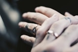 Close-up of intertwined hands with wedding rings, symbolizing connection.