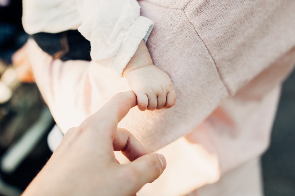 pessoa segurando a mão do bebê