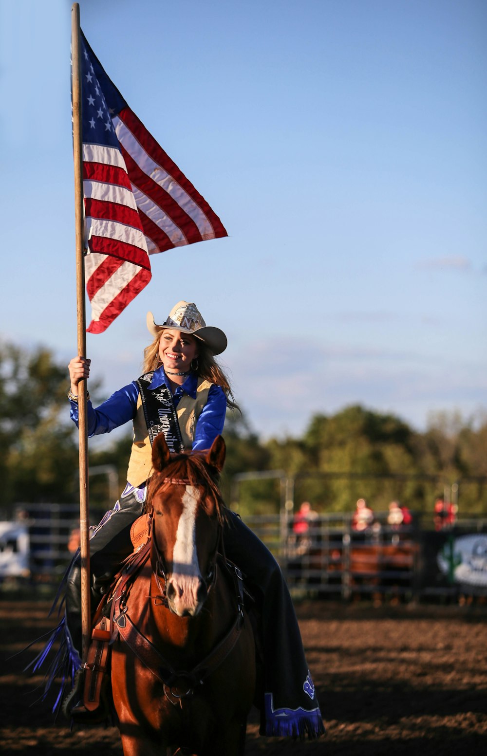 a woman riding on the back of a brown horse holding a flag