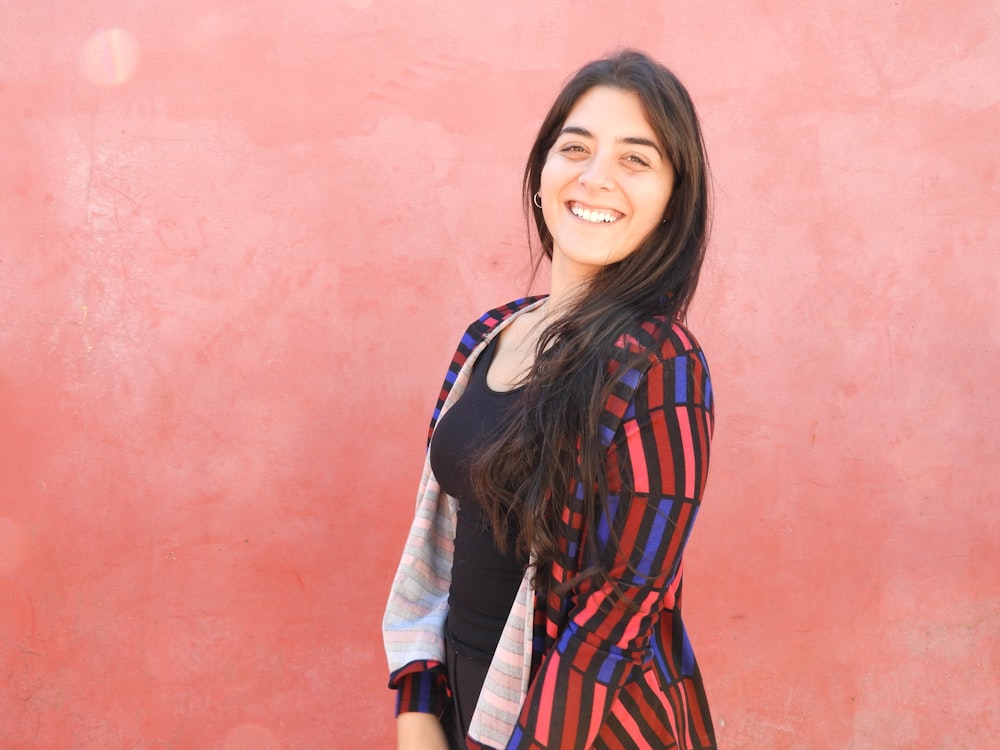 woman smiling while standing near pink wall