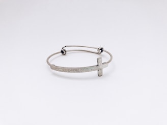 closeup photo of silver-colored cross bangle