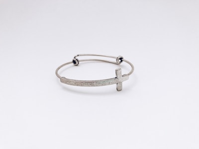 closeup photo of silver-colored cross bangle