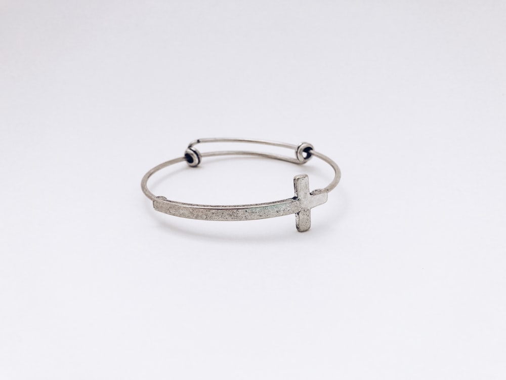 closeup photo of silver-colored cross bangle