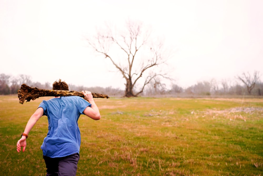 woman running on grass field holding firewood