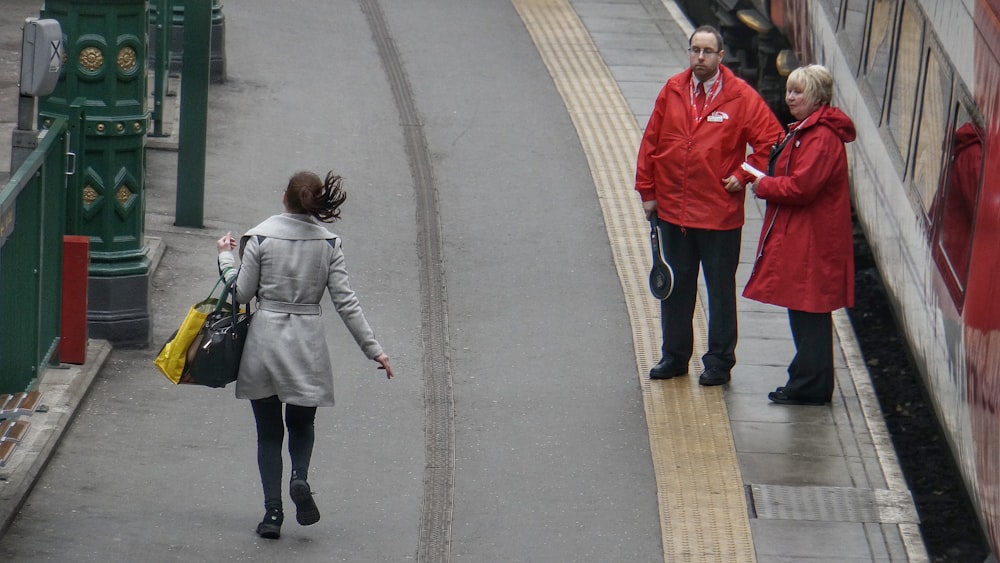 woman in gray coat walking on the road during day time