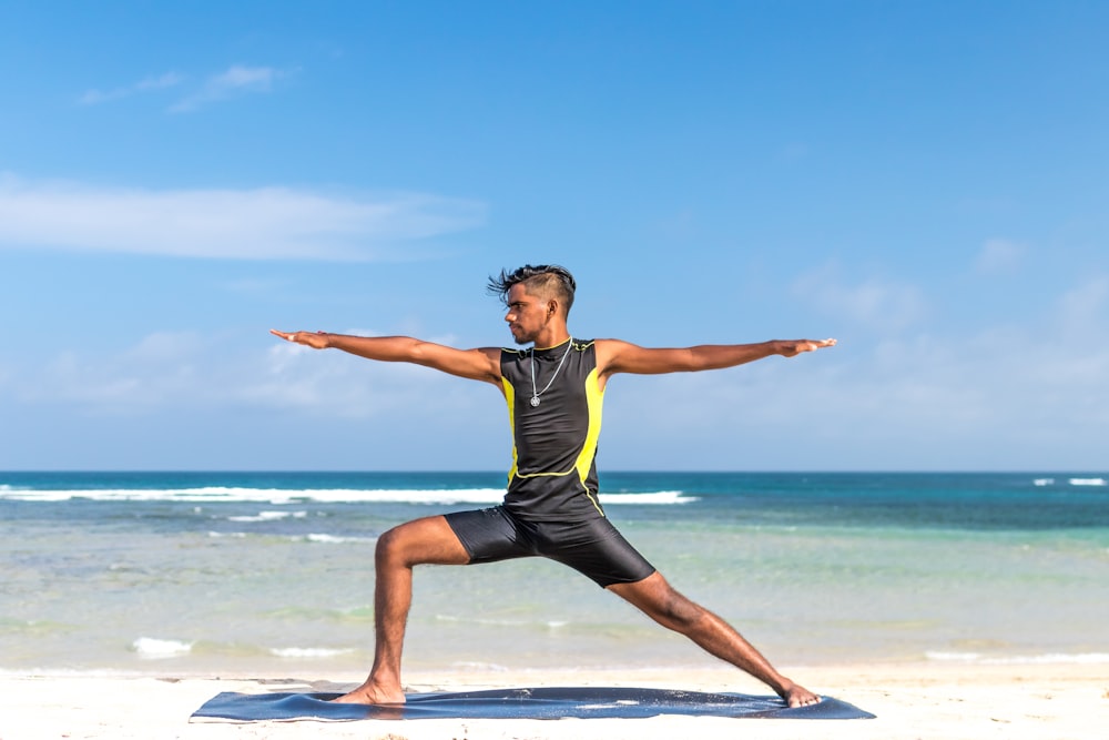 man standing at seashore while yoga