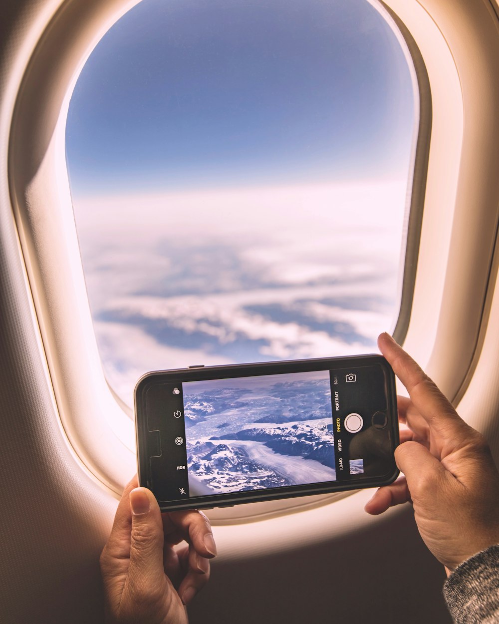 selective focus photography of person holding iPhone while taking photo of sky