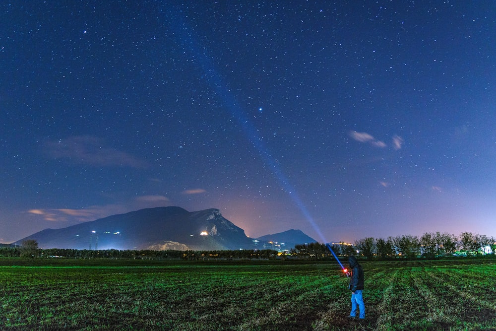 hombre de pie en el campo de hierba mientras mira al cielo