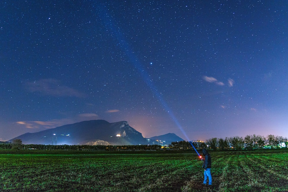man standing on grass field while looking at the sky
