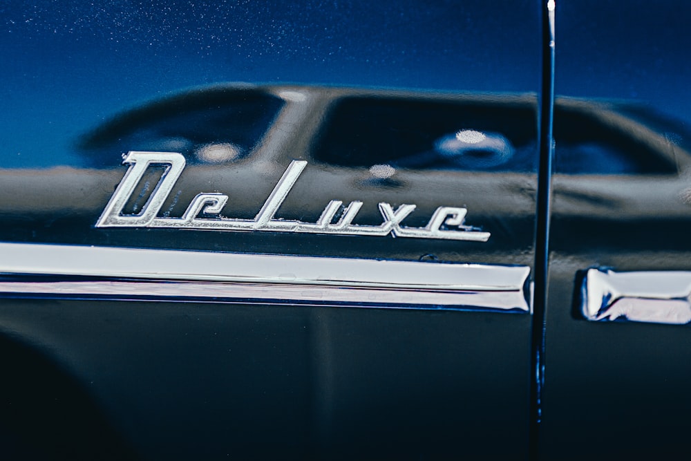 selective focus photography of chromed deluxe car emblem