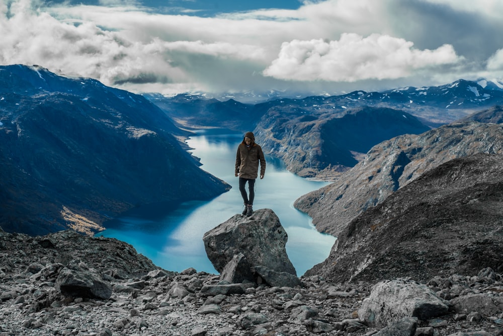 호수 근처의 회색 산에 서있는 남자