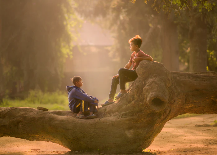 Two children sitting together outdoors in warm morning light