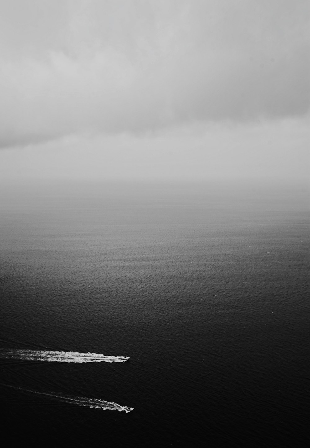 grayscale photography of two boats on a body of water