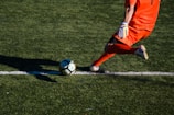 man kicking soccer ball on field