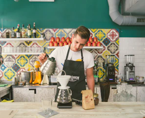 A skilled barista preparing a pour-over coffee with precision and care in a cozy setting.