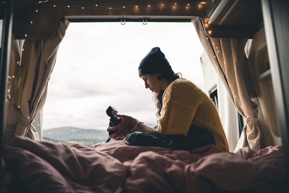 girl sitting on bed near window during daytime