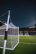 Close-up of a soccer ball on a vibrant green pitch under stadium lights.