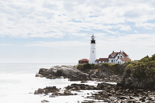 white lighthouse near brown and white house in Portland Head Lighthouse United States