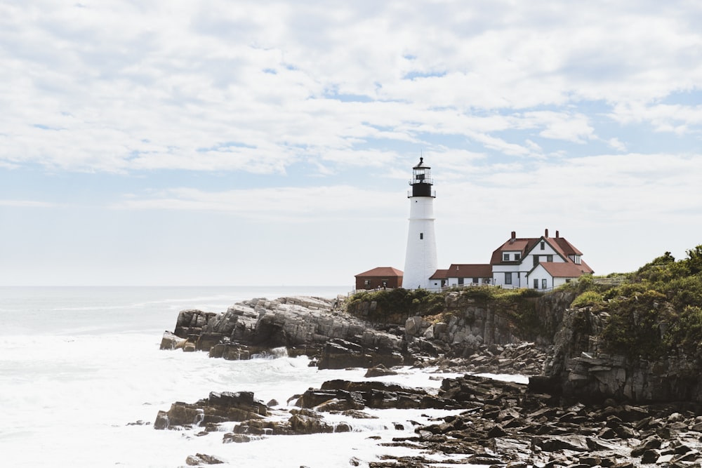 white lighthouse near brown and white house