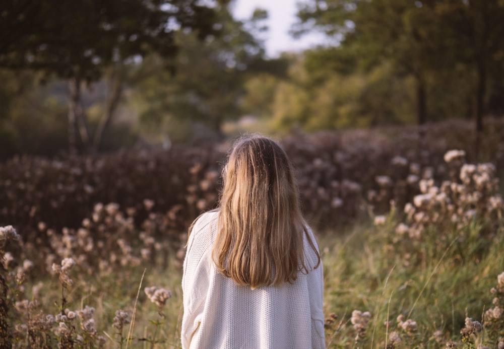 woman back surrounded by green and brown grass