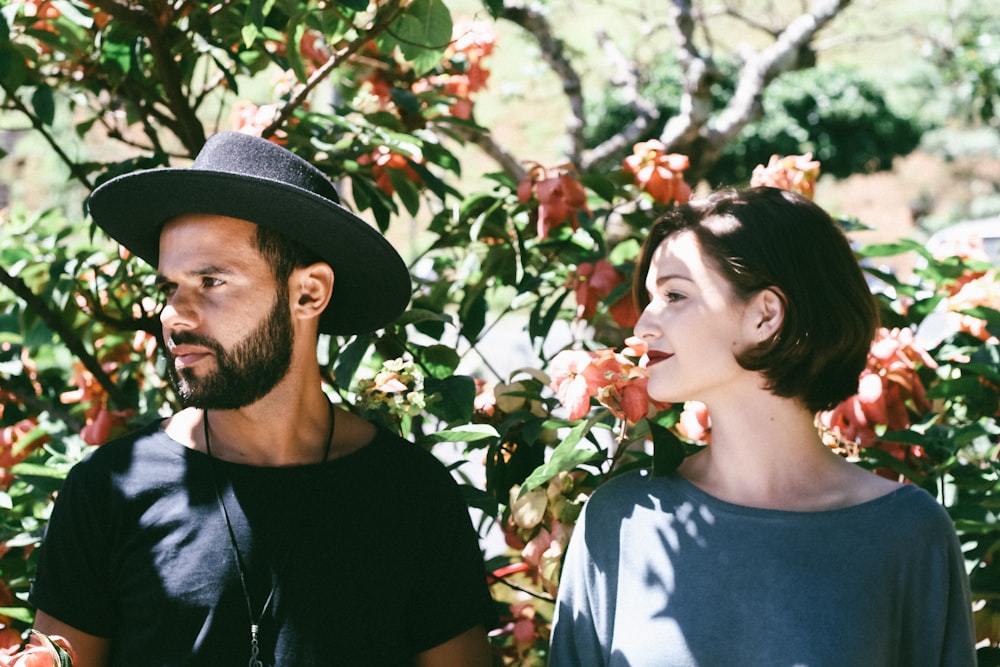 woman standing beside man wearing black hat