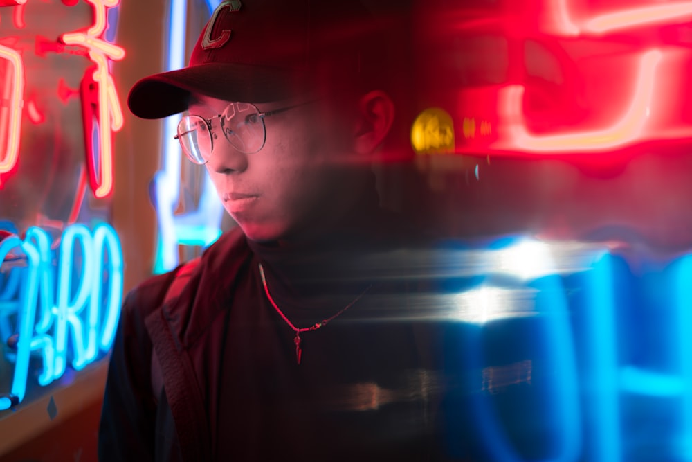 man standing near red and blue neon signages