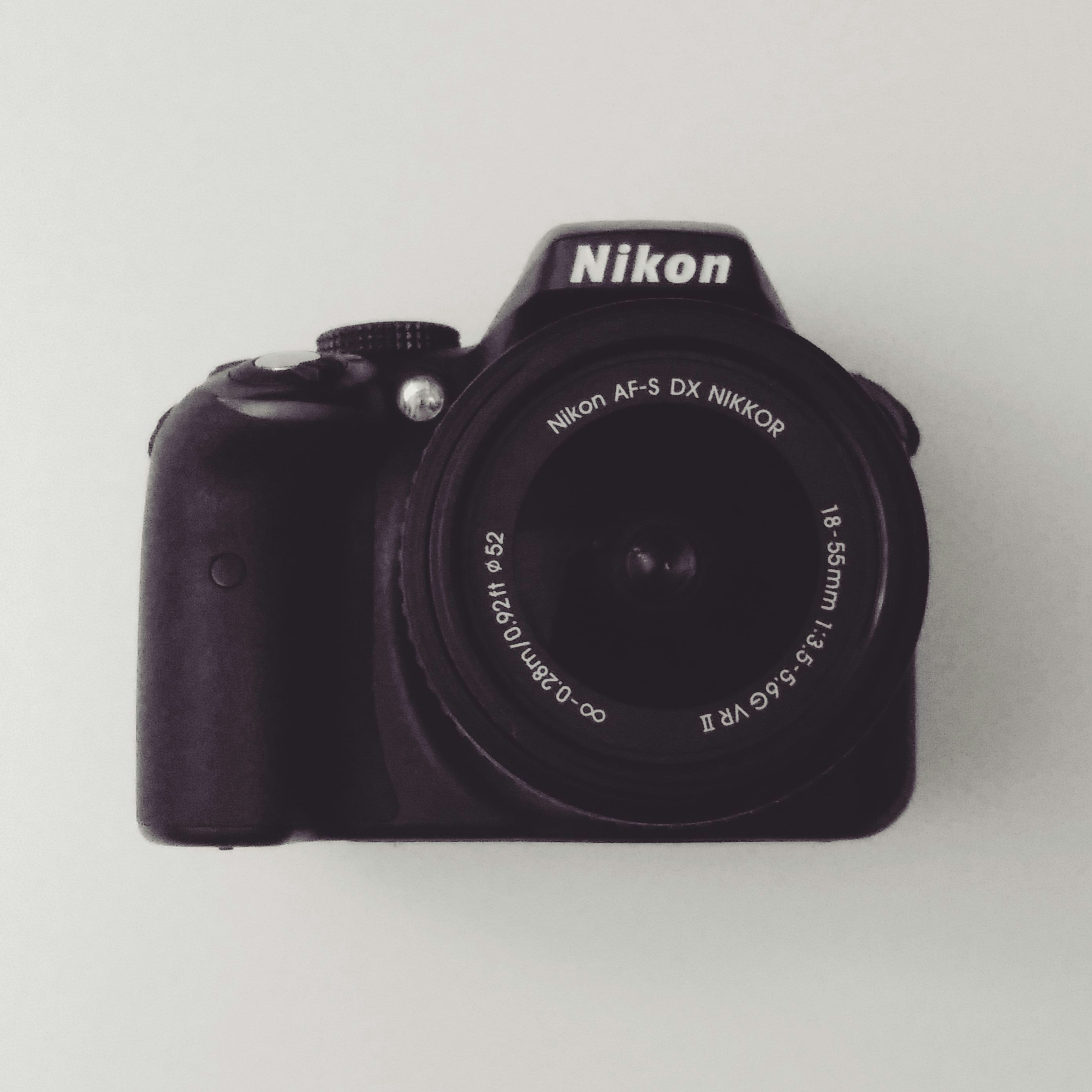 Nikon DSLR camera on white background with lens, clean product photography
