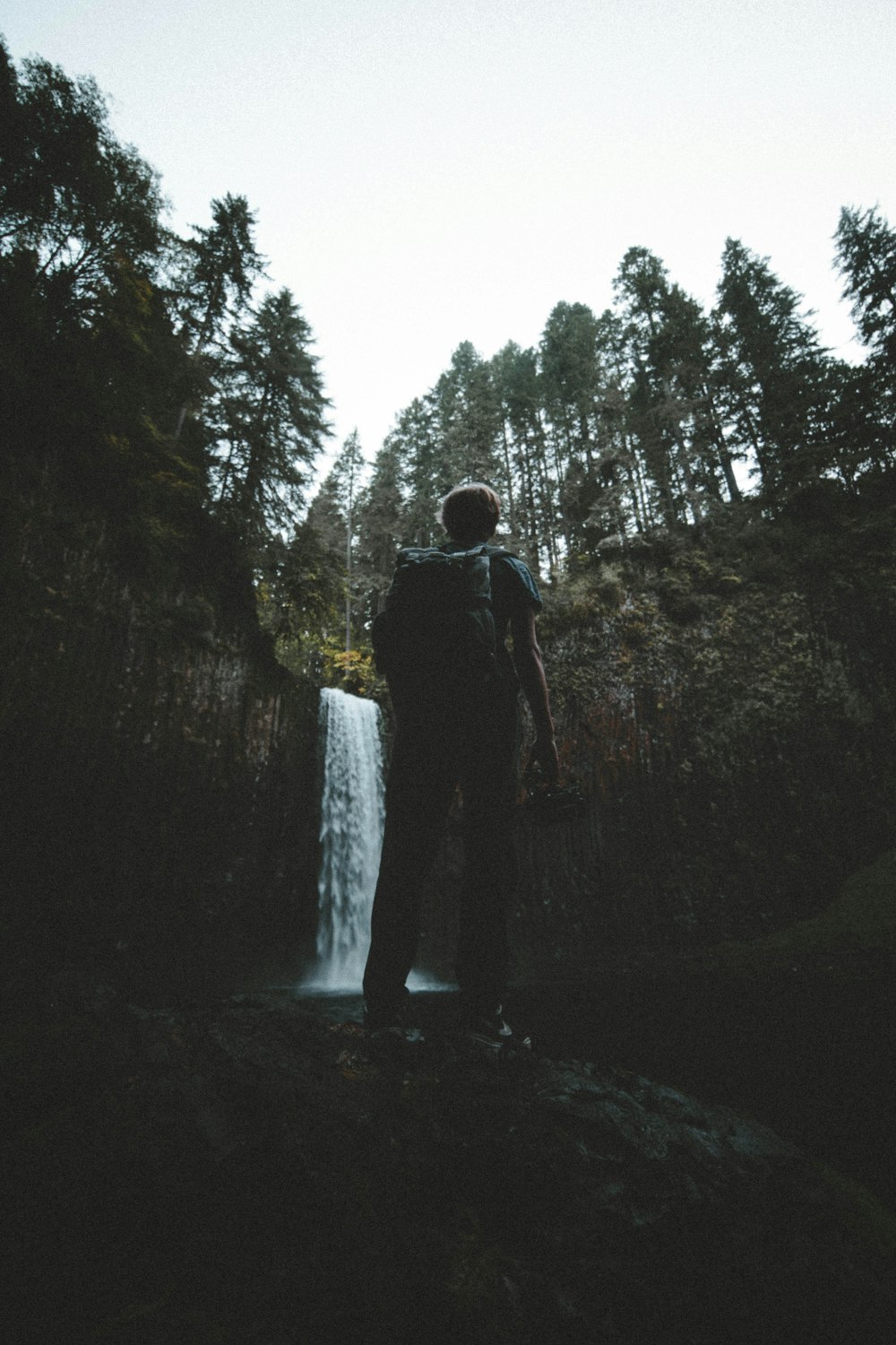 uomo in piedi davanti alle cascate durante il giorno