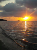 Sunset casting golden light over palm trees and calm sea on a small island