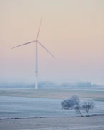 Wind turbines spinning gracefully along a misty coastline at dawn